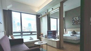 Une chambre d’hôtel moderne équipée d’un canapé, d’une petite table ronde, d’un lit et d’une tél évision.