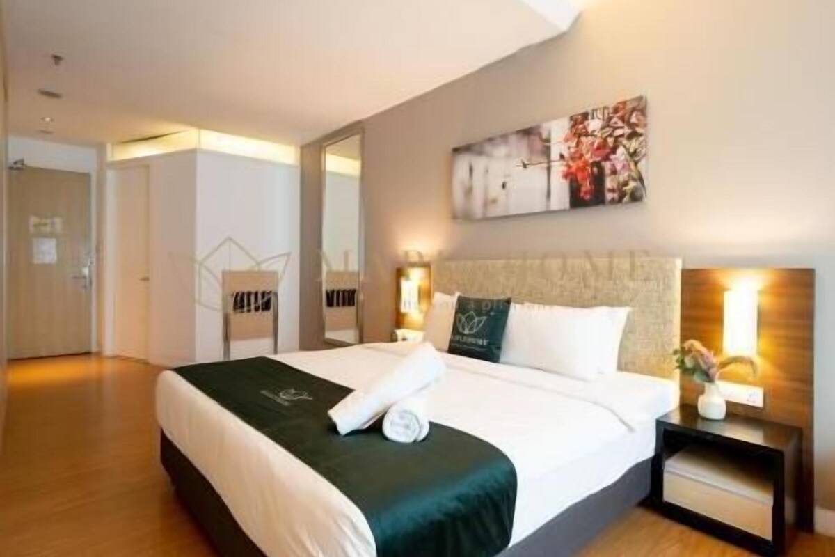 A hotel room with a bed, a nightstand, a wall-mounted artwork, and a mirror.