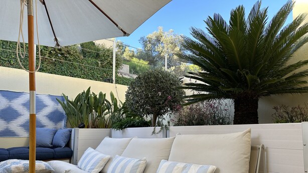 An outdoor seating area with a sofa, cushions, and a woven ottoman. - 6B Fabrica Velha Amazing Apartment Close TO THE (Lagoa)