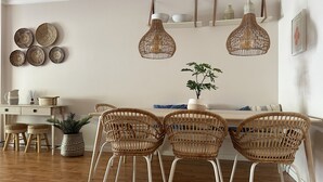 A dining area with wicker chairs, a wooden table, and hanging wicker light fixtures. - 6B Fabrica Velha Amazing Apartment Close TO THE (Lagoa)