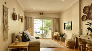 A living room with a sofa, a coffee table, a TV, and a dining area with stools. - 6B Fabrica Velha Amazing Apartment Close TO THE (Lagoa)