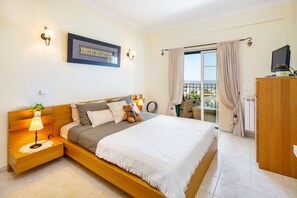 Un dormitorio con cama, lámparas de noche, mesita de noche, cómoda y vistas al exterior.
