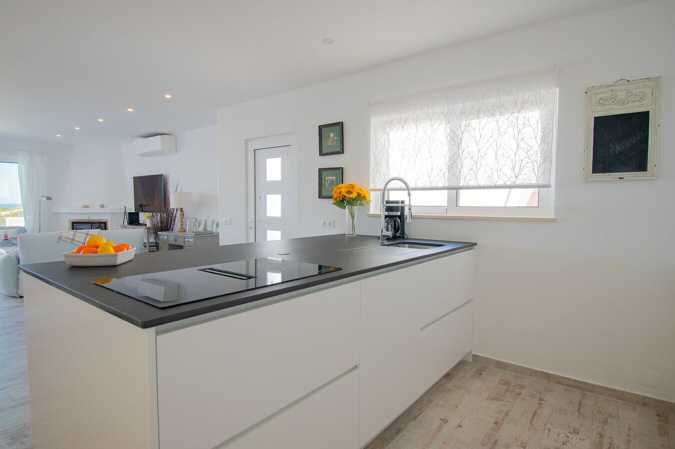 A modern kitchen with a central island, a built-in oven, and a window with a view.