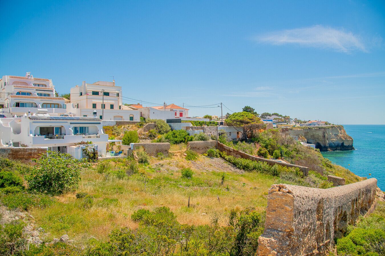 Ein Küstendorf mit weißen Häusern, einer felsigen Klippe und dem Meer.