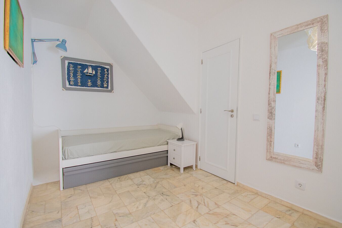 Un dormitorio con una cama litera, una mesita de noche, una lámpara de pared, una puerta y un espejo.