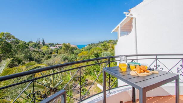 A balcony with a table set for breakfast, overlooking a coastal landscape. - 115 Vale do Milho - Vista do Mar (Lagoa)