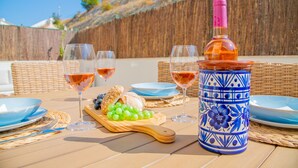 A table set with plates, glasses, a bottle, and a wooden board with grapes and bread. - Casa Flor do Mar in Carvoeiro (Lagoa)
