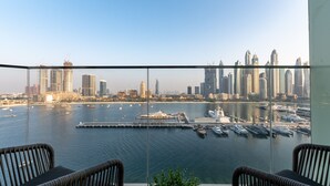 Ein Balkon mit Korbstühlen mit Blick auf einen Yachthafen und eine Skyline.