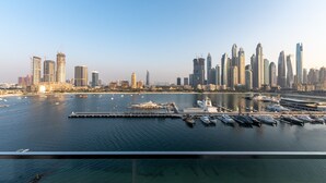 Eine Marina mit vertäuten Yachten, im Hintergrund ein Stadtpanorama und ein klarer Himmel.