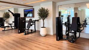 Ein moderner Fitnessraum mit Trainingsgeräten, einem großen Spiegel und einem Fernsehbildschirm, der Trainingsinformationen anzeigt.
