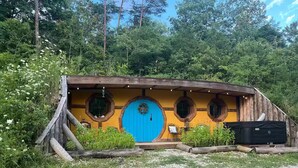 A Hobbit-style house with a blue door, wooden walls, and multiple windows.