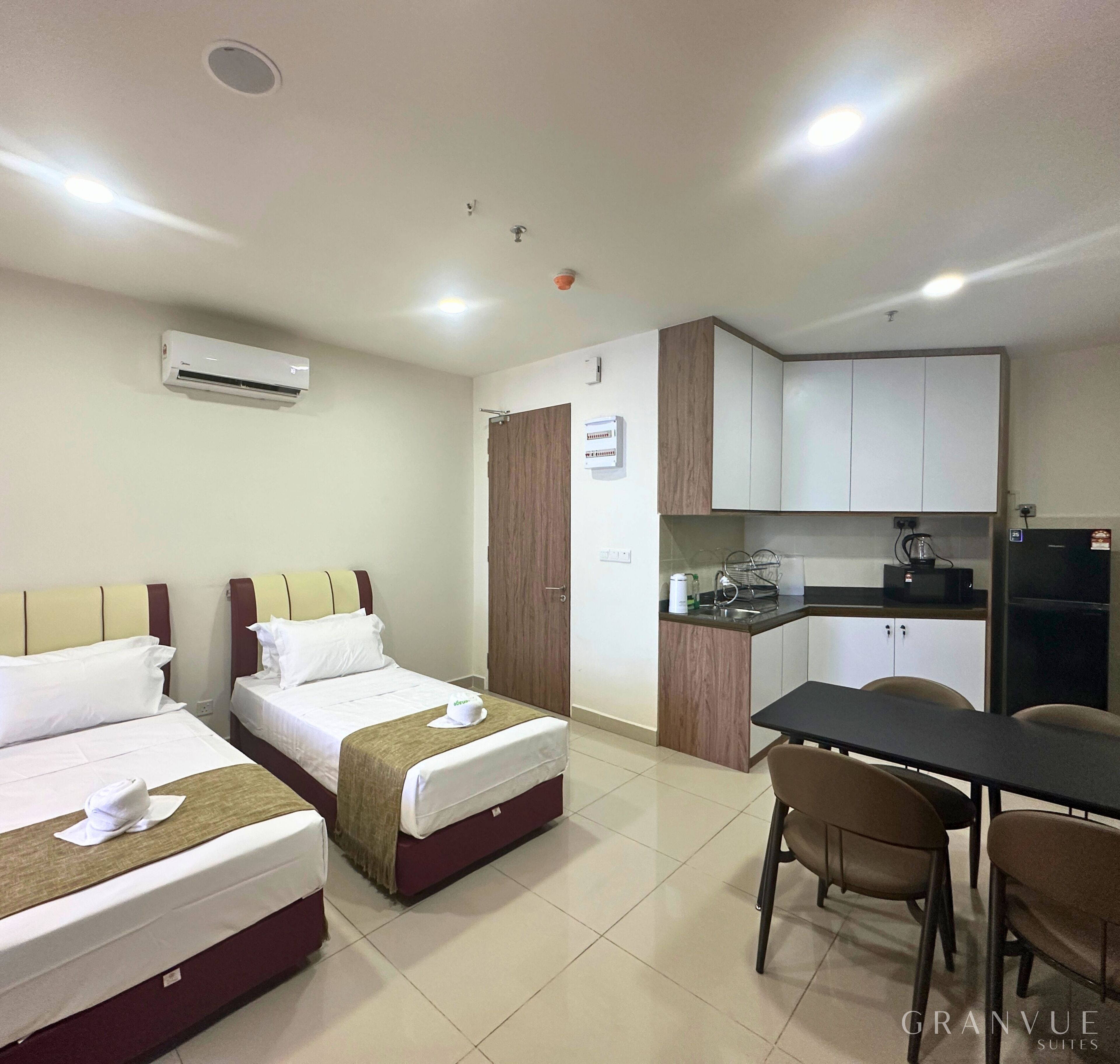 Une chambre d’hôtel avec deux lits, une kitchenette et un coin repas.