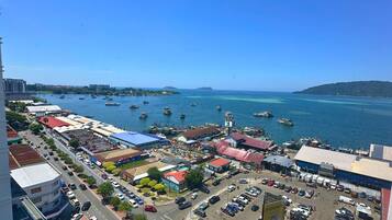 A coastal cityscape with a marina, commercial buildings, and a clear blue sky.