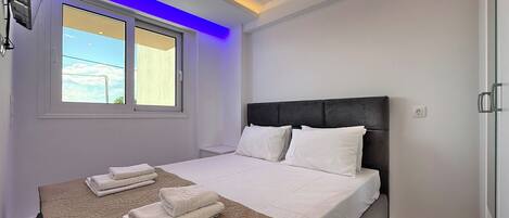 A modern bedroom with a large bed, a window, and a ceiling light.