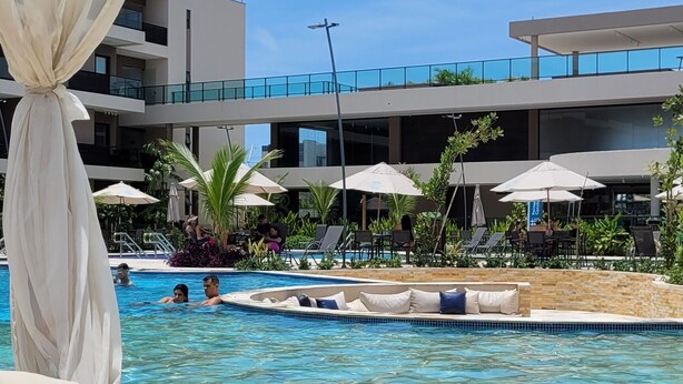A poolside area with a dining table set with fruits and a white canopy. - Refuge By Paty - Malia Beach Resort for families (Ipojuca)