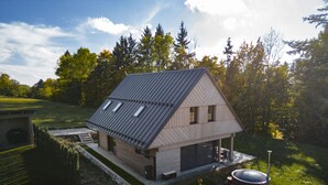 Ein modernes Haus mit einem geneigten Dach, einer überdachten Veranda und einem gepflegten Rasen.