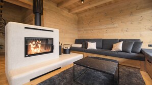 Ein gemütliches Blockhaus-Interieur mit Kaminofen, einer Couch und einem Couchtisch.