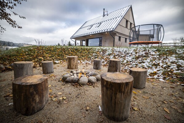 A modern house with a sloped roof, a fire pit, and wooden stumps arranged in a circle. - Vysok nad Jizerou Lvta052 (Vysoké nad Jizerou)