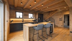 A modern kitchen with wooden beams, a central island with bar stools, a built-in stove, and a large window. - Vysok nad Jizerou Lvtu051 (Vysoké nad Jizerou)