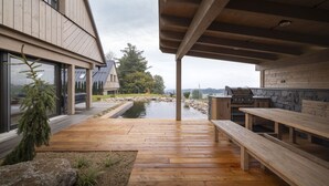A wooden deck with benches, a stone wall, and a view of a house with large windows and a stone fireplace. - Vysok nad Jizerou Lvtu051 (Vysoké nad Jizerou)