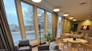 A spacious room with large windows, a dining area, and a flat-screen TV mounted on the wall. - Motellet Karlskrona (Karlskrona)