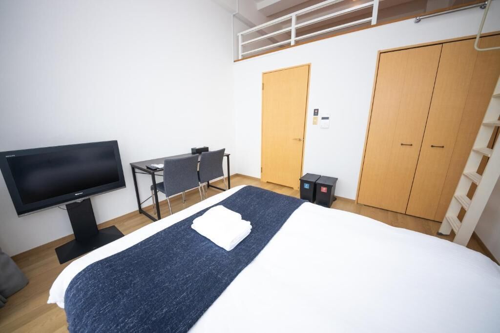Hotellihuone, jossa on sänky, työpöytä, televisio ja vaatekaappi.