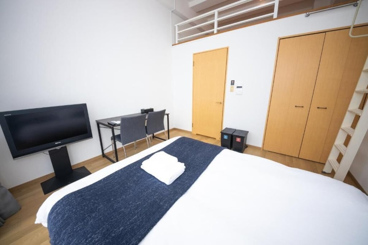 Ein Hotelzimmer mit Bett, Schreibtisch, Fernseher und Kleiderschrank.