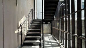 Eine enge Treppe mit Metallgeländern, die zu einem überdachten Bereich mit Metalldach führt.