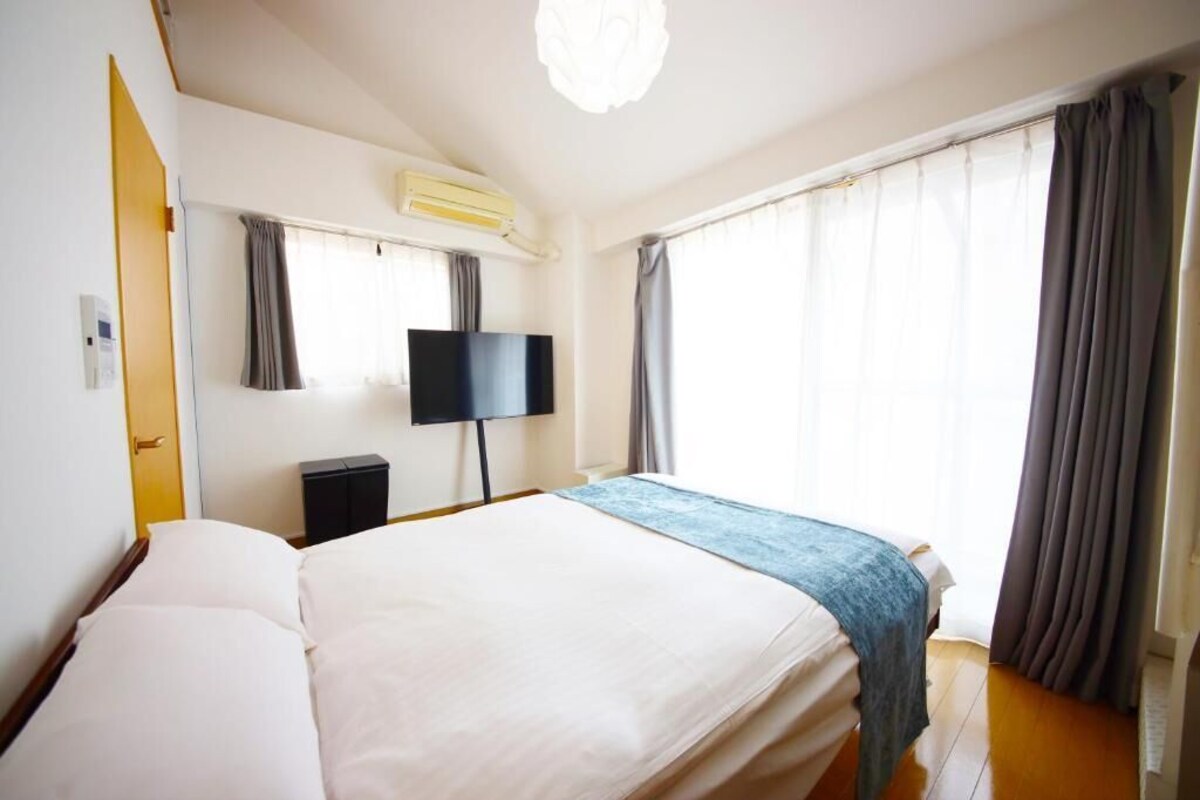 Ein Hotelzimmer mit einem Bett, einem Fernseher, einer Klimaanlage und einem Fenster mit Vorhängen.