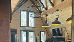 A rustic kitchen with a central island, wooden ceiling beams, and large windows. - Cozy 2-bedroom secluded A-Frame cabin in charming Murray (Murray)