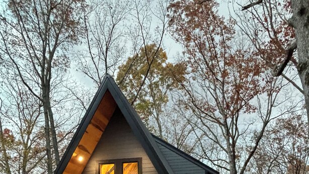 A modern cabin with a sloped roof, large windows, and a porch with outdoor seating. - Cozy 2-bedroom secluded A-Frame cabin in charming Murray (Murray)
