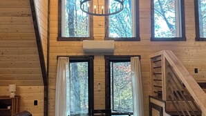 A wooden cabin interior with a dining table, chairs, a chandelier, and a staircase. - Cozy 2-bedroom secluded A-Frame cabin in charming Murray (Murray)