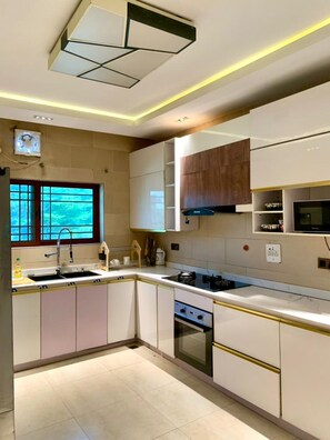 Appartement | Privékeuken | Een koelkast, een magnetron, een oven, kookgerei, borden en bestek