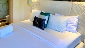 A modern hotel room with a large bed, a marble headboard, and a view of the bathroom. - Sujimoto Residences - The AVEs  (Lagos)