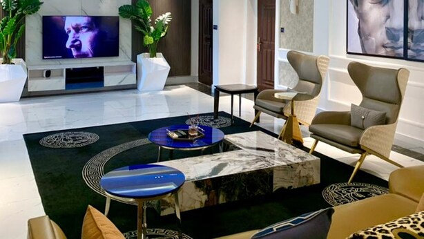 A modern living room with a flat-screen TV, a chandelier, and a large painting. - Sujimoto Residences - The AVEs  (Lagos)