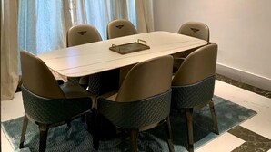 A modern dining area with a round table, six chairs, and a ceiling light fixture. - Sujimoto Residences - The AVEs  (Lagos)