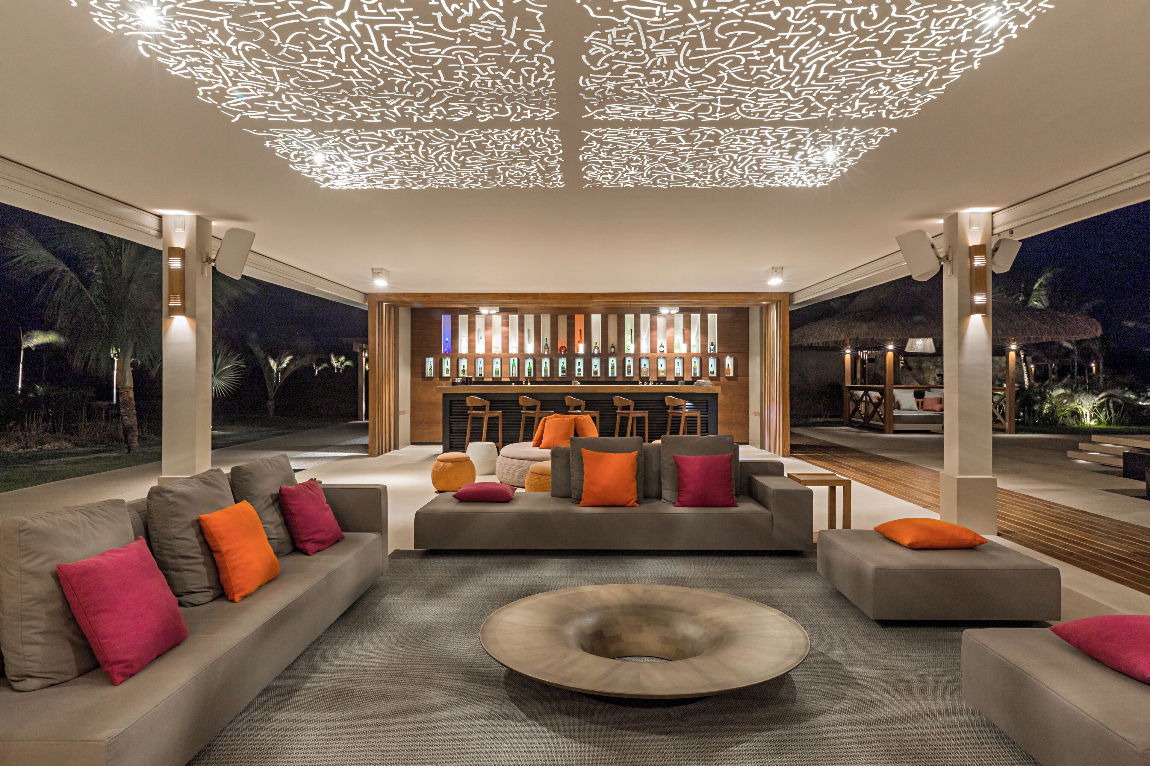 A modern living room with a sofa set, a coffee table, and a bar area with stools.