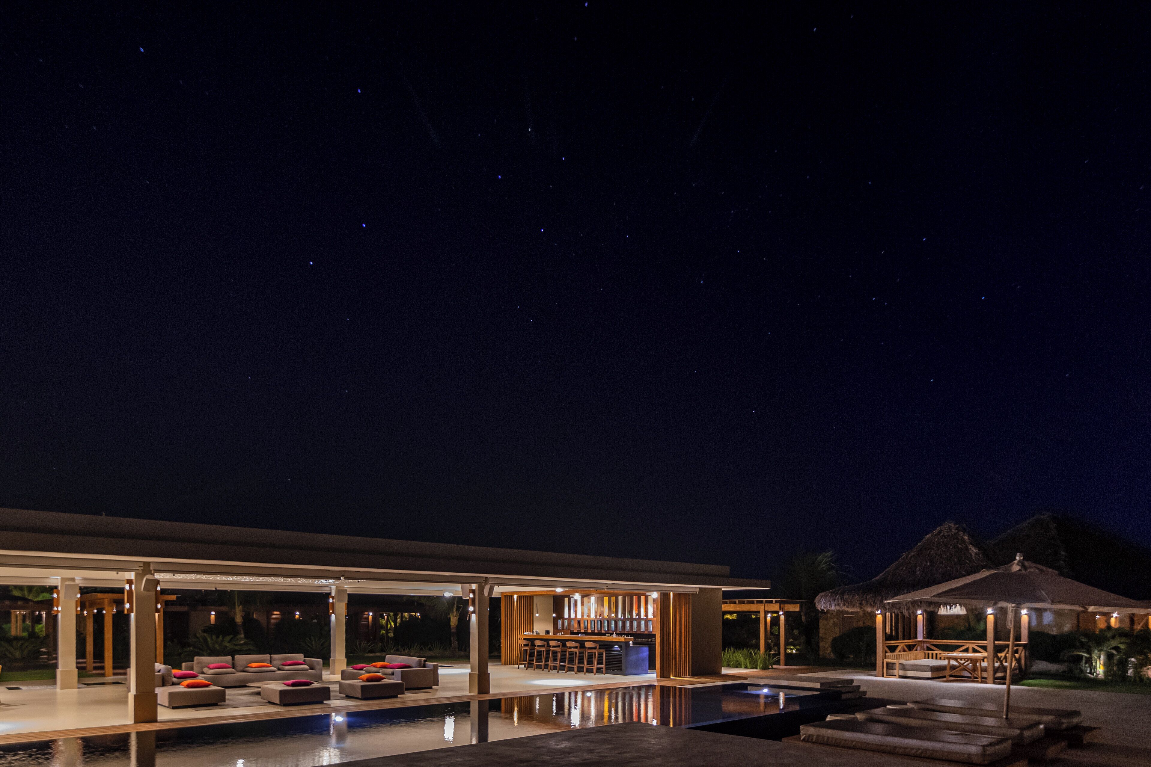 Un moderno resort con piscina, zona de estar exterior y bar.