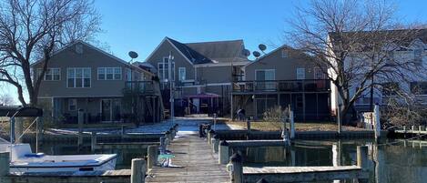 A wooden pier leading to a marina with houses in the background.