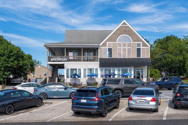 A building with a sign reading "BREAKFAST" and a parking lot with various cars. - Sunrise Veranda-Back Creek Villa with Sunroom (Solomons)