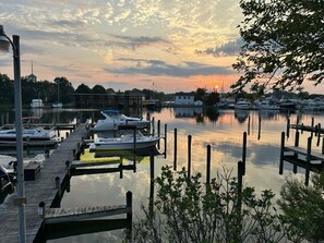 A marina with boats docked at wooden piers, surrounded by trees and a clear sky. - Sunrise Veranda-Back Creek Villa with Sunroom (Solomons)