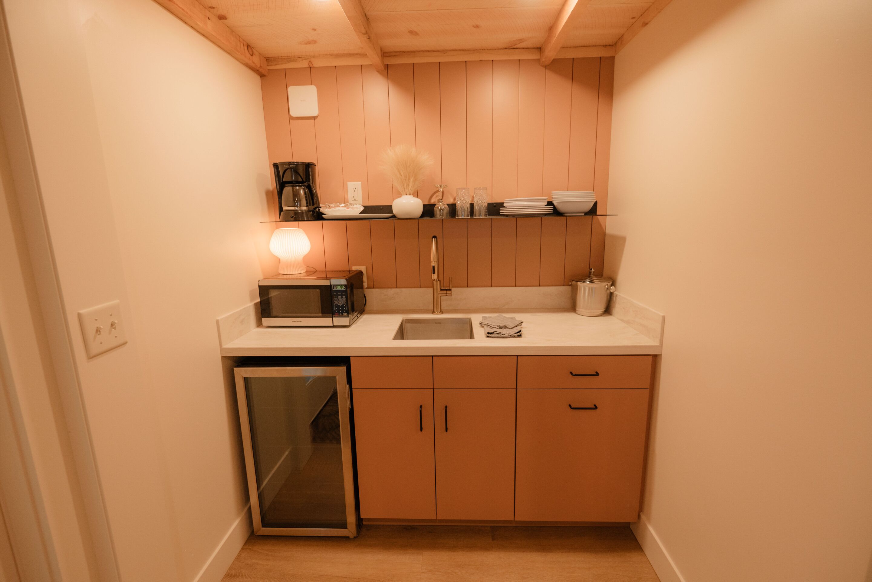 A compact kitchen with a microwave, coffee maker, and a sink.