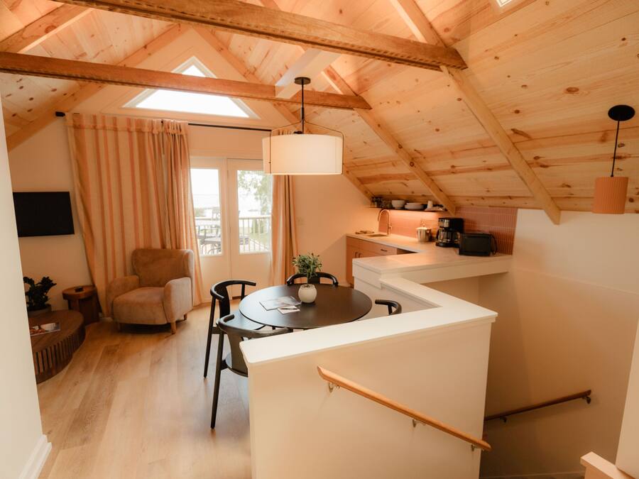 Une pièce confortable de style loft, comprenant un coin repas, une cuisine et un escalier.