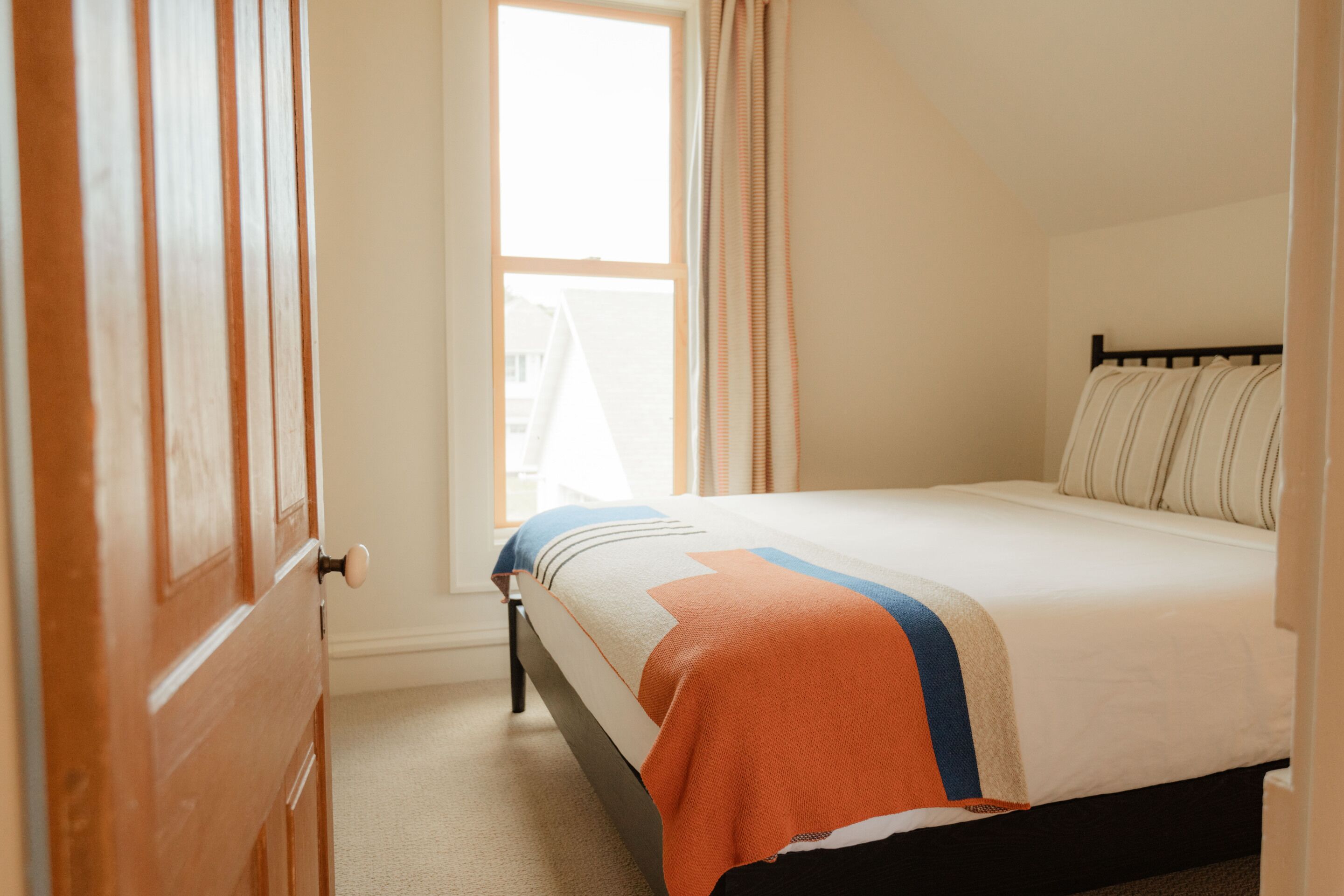A bedroom with a bed, a window, and curtains.