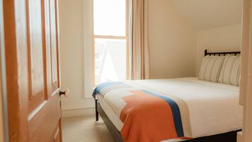 A bedroom with a bed, a window, and curtains.