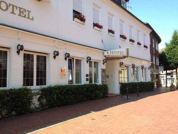 A white building with a sign reading "HOTEL" and multiple windows with shutters.