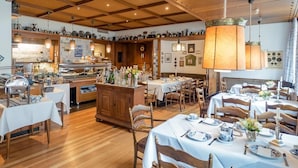 A restaurant with wooden interiors, multiple dining tables, and a buffet area. - Posthotel Monegro  (Steinfurt)