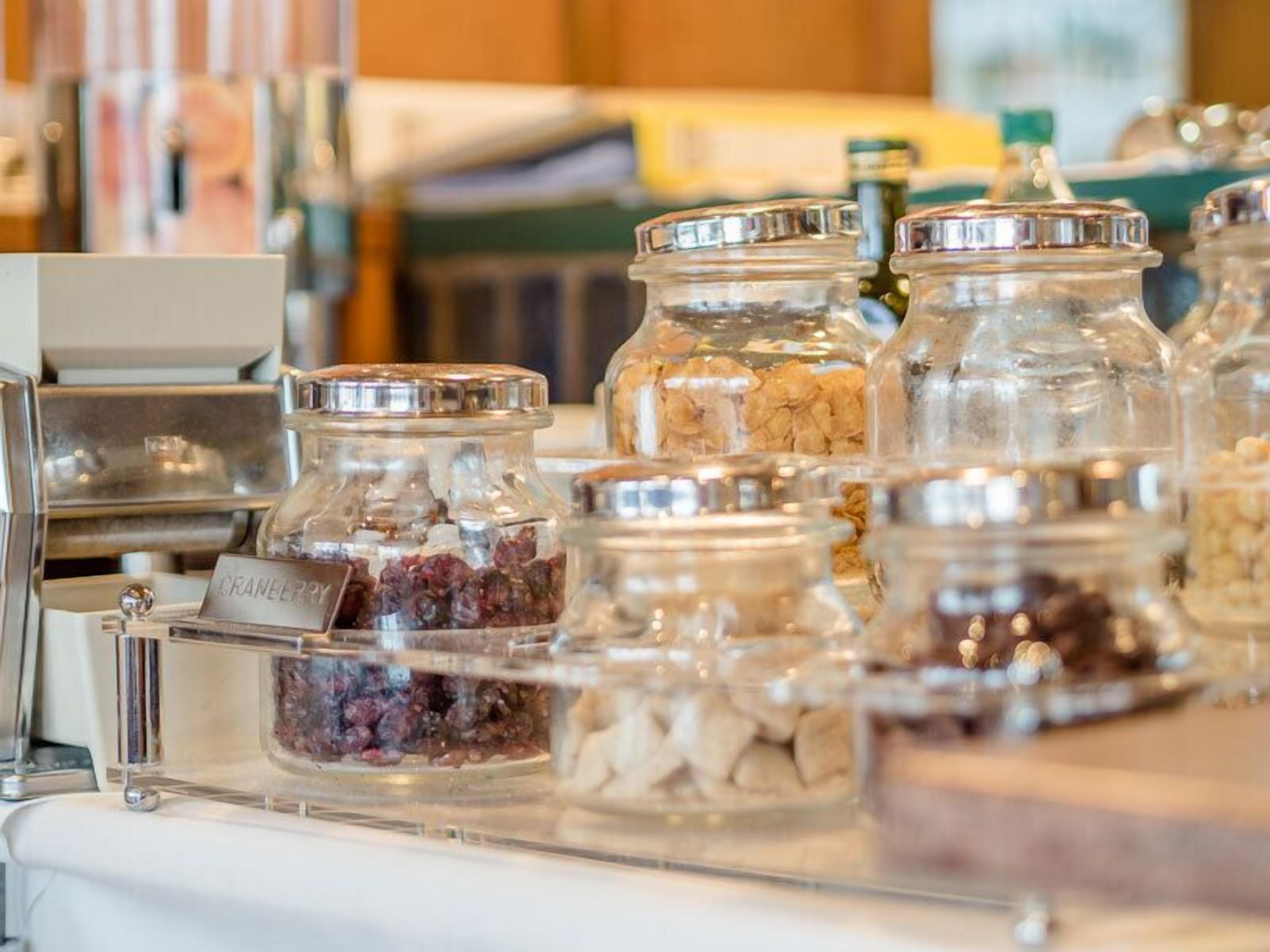 A display of various food items in glass jars with metal lids, arranged on a counter.