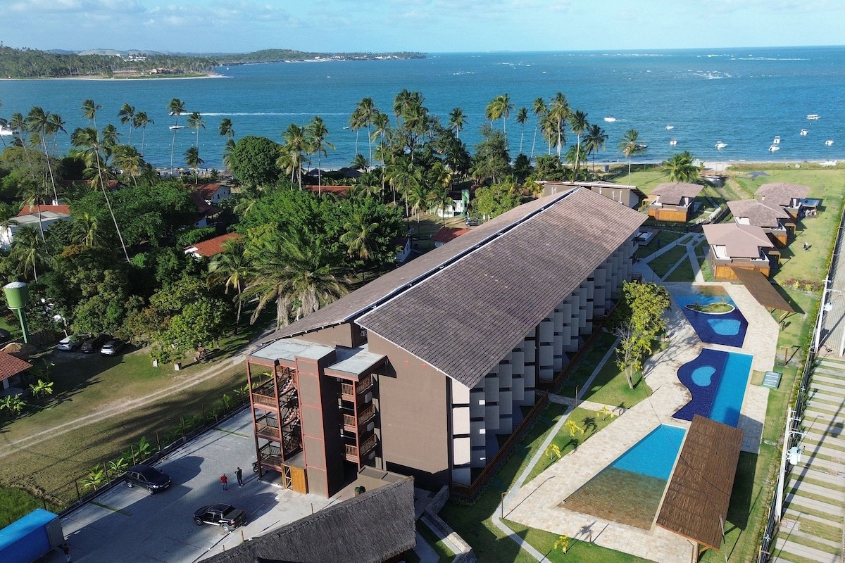 Um resort com um edifício extenso, uma piscina e vista para o oceano.
