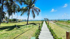 A pathway leading to a beach with palm trees and a clear sky. - Atlântico Carneiros - Pé na areia  (Tamandaré)